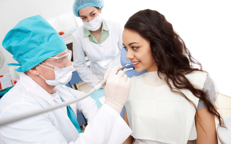 Dentist examining patient's teeth during dental crown aftercare consultation.