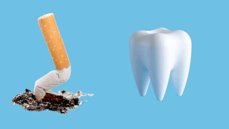 Broken cigarette and ash next to a healthy white tooth, illustrating smoking's negative impact on oral health.