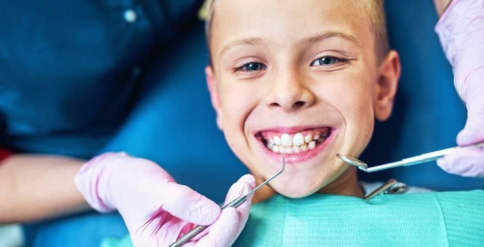 Young child smiling during dental examination with dentist using mirror and explorer tool in Castro Valley.