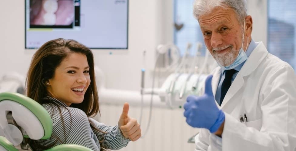 Smiling patient giving thumbs up with senior dentist in Castro Valley dental office.