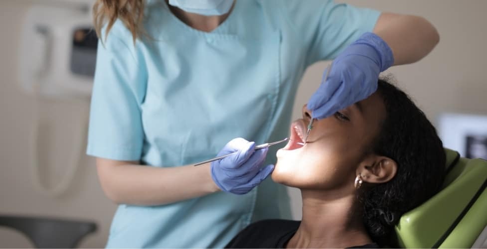 Dental hygienist applying protective sealant to patient's teeth during preventive treatment.