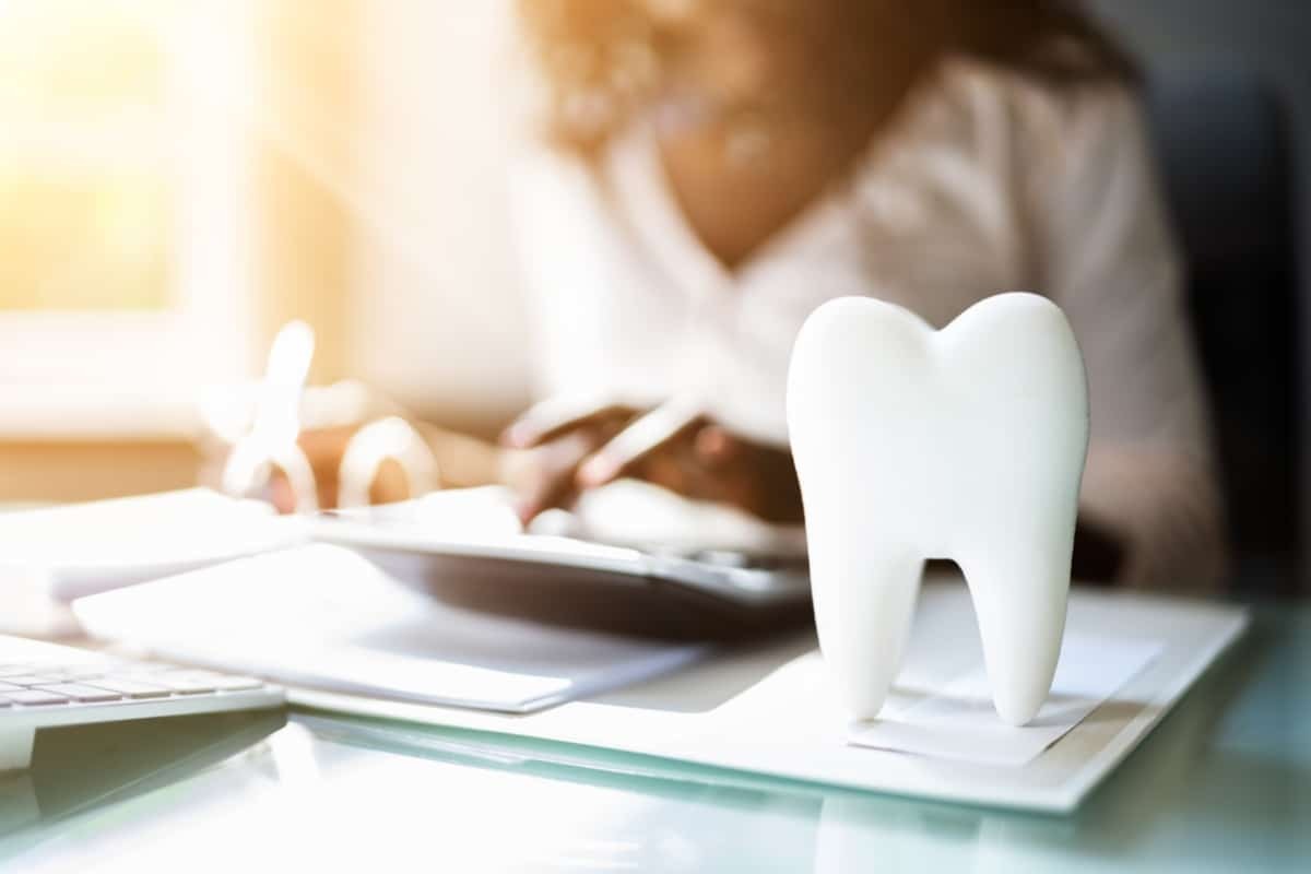 Dental professional reviewing patient benefits and insurance coverage at desk with tooth model.