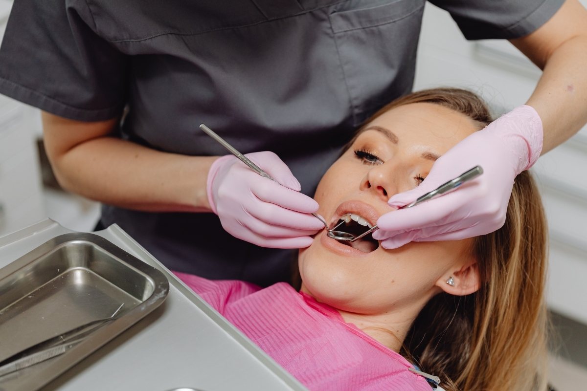 Dentist examining patient's teeth during dental procedure with protective gloves and instruments.