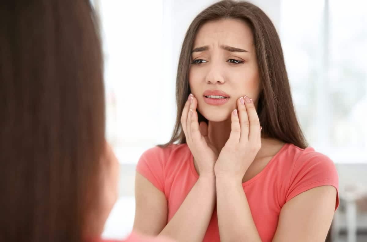 Woman experiencing tooth pain, holding her cheek in discomfort at a Castro Valley dental office.