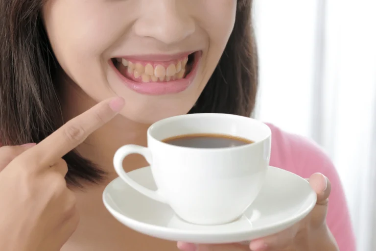Smiling woman pointing at a cup of coffee