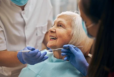 Dentist examining a smiling older woman’s teeth