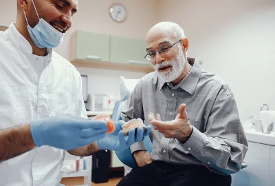 Dentist talking with an older man in the dental chair