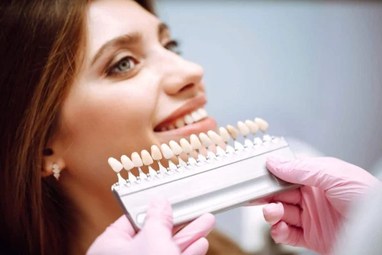 Dentist holding a veneer shade guide next to a smiling woman