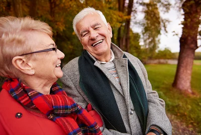 Older couple laughing together on a park bench